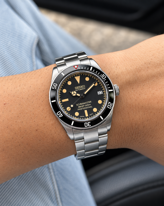 Scubamaster 58 en la muñeca, con esfera negra, índices dorados y brazalete de acero